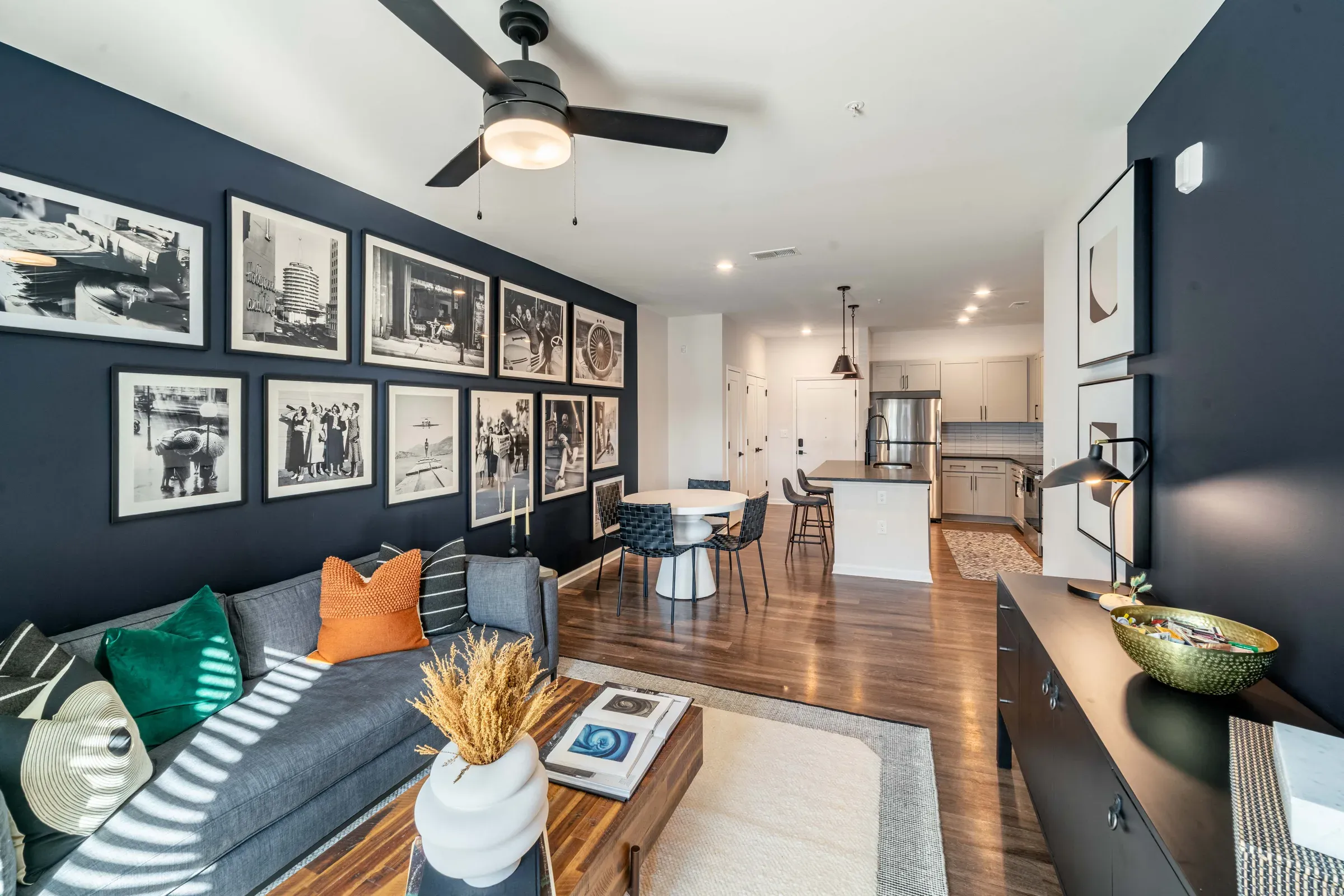 Modern living room with gallery wall, gray sofa, coffee table, and view into dining area and kitchen.